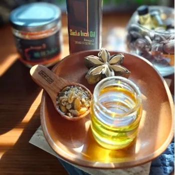 營養補給專家的印加果油瓶子和一勺印加果仁擺放在木碗中，背景有更多的印加果產品
