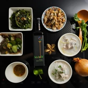 一瓶營養補給專家的Sachs Inchi Oil擺放在各種菜餚和食材之間，背景為黑色桌面